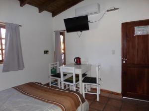 a bedroom with a bed and a desk with a television at Abril in Cafayate