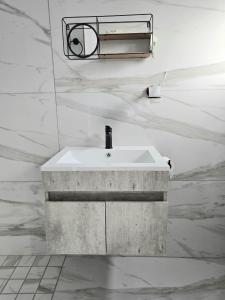 Baño con lavabo blanco y paredes de mármol en Aqua Breeze, en Ciudad del Cabo