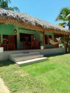 a green house with a thatched roof at Casa da Lagoa - Pousada Icaraí Kite Village in Amontada