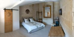 a bedroom with a bed and a table and a mirror at Le Joubert Hôtel Particulier in Uzès