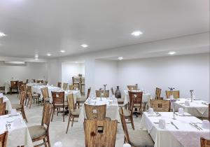 uma sala de jantar com mesas e cadeiras com toalhas de mesa brancas em Olmeca Plaza Urban Express em Villahermosa