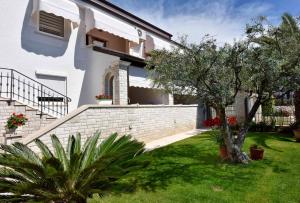 Biały dom z ogródkiem z drzewem w obiekcie Apartments in Porec - Istrien 40311 w Poreču