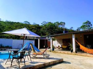 a patio with chairs and an umbrella and a slide at Casa de campo Maria&Maria próximo a cidade de Juiz de Fora MG in Juiz de Fora