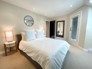 a bedroom with a large white bed and a mirror at Modern Home with Forest Views by Harmony Whistler in Whistler