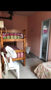 a room with a bunk bed and a chair and a table at Casa confortável a 5 minutos da Praia do Forte a pé in Cabo Frio +9 photos