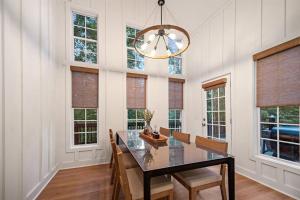 a dining room with a table and chairs and windows at NEW White Pine Hideaway Fire pit Hot Tub Games in Ellijay