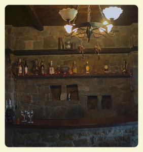 a bar with a stone wall with bottles and a chandelier at Voreas Hotel in Kato Loutraki