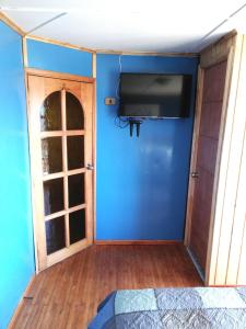 um quarto com uma parede azul e uma televisão de ecrã plano em La Casa Colores em Puerto Montt