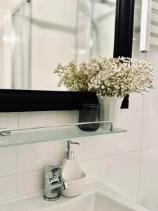 a bathroom sink with a mirror and a vase of flowers at Apartament Zielony Stół in Gniezno +21 photos