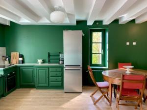 a green kitchen with a table and a refrigerator at Clos des Mésanges in Chisseaux