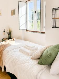 a white bed in a room with a window at Casinha da Serra in Vilar