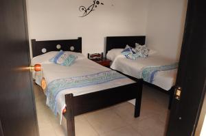 阿基塔尼亚Hotel Guaquira Real的一间卧室配有两张带蓝白色床单的床