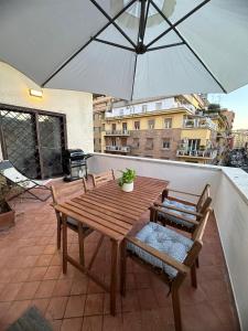 un tavolo in legno con sedie e ombrellone su un balcone di L'Attichetto di via Padova a Roma