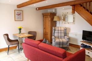 a living room with a red couch and a table at School House Cottage in Buxton