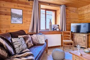ein Wohnzimmer mit Sofa und Fernseher in der Unterkunft Résidence Les Granges - Chalet spacieux · Centre village des Granges · Sauna MAE-0184 in Saint-Marcel