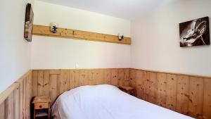 ein Schlafzimmer mit Holzvertäfelung und einem weißen Bett in der Unterkunft Résidence Les Cristaux - Appartement rénové · Proche des pistes · Balcon · Sauna · WIFI · Hammam MAE-0424 in Levassaix