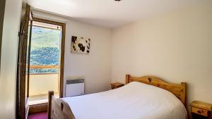 ein Schlafzimmer mit einem Bett und einem Fenster in der Unterkunft Résidence Les Cristaux - Appartement spacieux & rénové · Proche des pistes · Balcon · Sauna · Hammam · WIFI MAE-0524 in Levassaix