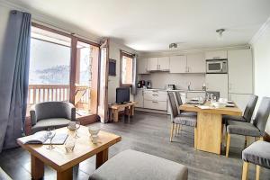 ein Wohnzimmer mit Tisch und Stühlen und eine Küche in der Unterkunft Résidence Les Cristaux - Appartement confortable et rénové · Proche des pistes · Balcon · Sauna · Hammam · WIFI MAE-0674 in Levassaix