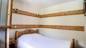 Schlafzimmer mit einem weißen Bett und Holzwänden in der Unterkunft Résidence Les Cristaux - Appartement spacieux · Proche des pistes · Balcon · Sauna · Hammam · WIFI MAE-0604 in Levassaix