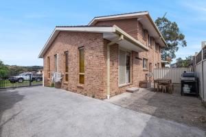 a brick house with a patio and a grill at Casada South West Rocks in South West Rocks