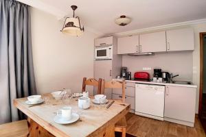 eine Küche mit einem Holztisch mit Geschirr darauf in der Unterkunft Résidence Les Cristaux - Appartement de standing rénové · Proche des pistes · Balcon · Sauna · Hammam · WIFI MAE-1164 in Levassaix + 17 Fotos