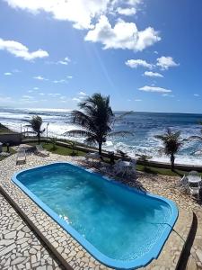 a swimming pool with the ocean in the background at Casa de praia Vista Mare Beira-mar in Barra de São Miguel
