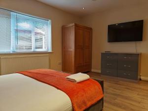 a bedroom with a bed and a dresser with a flat screen tv at Stunning 5-bed House near NEC & BHX in Solihull