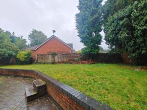 a house with a brick wall and a bench in a yard at Stunning 5-bed House near NEC & BHX in Solihull