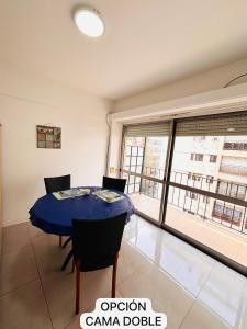 a dining room with a blue table and a large window at Mar del Plata Departamento Zona Aldrey in Mar del Plata