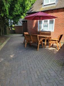 een houten tafel en banken met een paraplu bij Luxury 5-bed House near NEC & BHX in Solihull