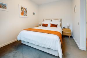 una camera da letto con un grande letto bianco con una coperta arancione di Pavilions Marina Apartment 104 - Wynyard Quarter Viaduct Harbour ad Auckland Altre 30 foto