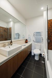 un bagno con lavandino, WC e specchio di Pavilions Marina Apartment 104 - Wynyard Quarter Viaduct Harbour ad Auckland