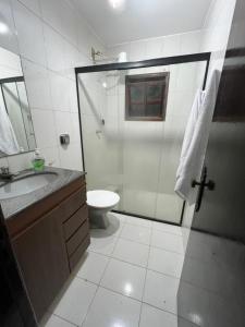 a bathroom with a shower and a sink and a toilet at Pousada e Restaurante Dona Lu in Itaperuna
