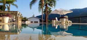 una piscina con sombrilla y palmeras en Casa Rural Caserío Las Viñas, en Guájar Fondón