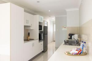 a white kitchen with white cabinets and appliances at Smart Suites Self Check-in Apartments - Freney Park Disk Golf Course in Brisbane