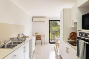 a white kitchen with white cabinets and a sink at Smart Suites Self Check-in Apartments - Freney Park Disk Golf Course in Brisbane +16 photos