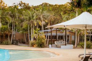 an umbrella next to a swimming pool with a house at NRMA Angourie Resort, Yamba in Yamba