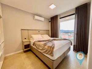 a bedroom with a bed and a large window at Aconchegante apartamento a 3 min. do Beto Carrero e Praia in São Lídio
