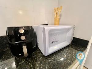 a microwave and a toaster sitting on a counter at Aconchegante apartamento a 3 min. do Beto Carrero e Praia in São Lídio