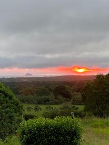 a sunset over a field with the sun in the distance at Cabaña de la Tortuga Gigante in Bellavista +2 photos