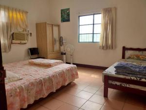 1 Schlafzimmer mit 2 Betten und einem Fenster mit einem Ventilator in der Unterkunft 西濱休息站旁 in Ta-an