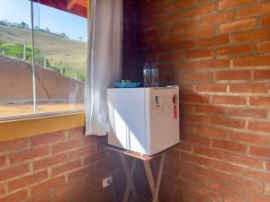 a refrigerator against a brick wall with water bottles on top at Chalés Paraíso na Roça São Bento do Sapucaí Bairro do Serrano in São Bento do Sapucaí