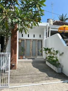 a white house with a gate and a tree at Permata Tojan Blok A3 in Ubud