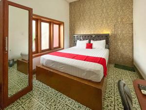 a bedroom with a large bed and a mirror at RedDoorz Syariah Near Alun-Alun Tulungagung in Tulungagung