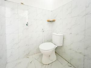 a white toilet in a white tiled bathroom at RedDoorz Syariah Near Alun-Alun Tulungagung in Tulungagung +59 photos