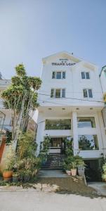 een wit gebouw met enkele planten ervoor bij Thanh Loan Hotel DL - by BAY LUXURY in Da Lat