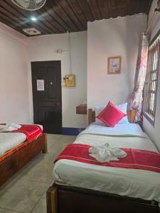 a bedroom with two beds with red and white sheets at Chitlatda Bila House in Luang Prabang