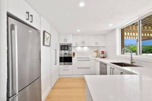 Una cocina blanca con electrodomésticos blancos y una ventana. en Magical Hardy's Bay Waterfront Apartment, en Killcare