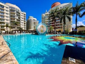 N6802 Cobertura Vista Mar Praia e Beto Carrero في بنها: حمام سباحة كبير مع أشجار النخيل والمباني