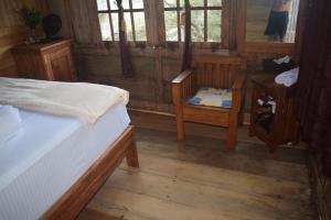 a room with two beds and a chair and windows at Areef Homestay Kaledupa in Kaledupa